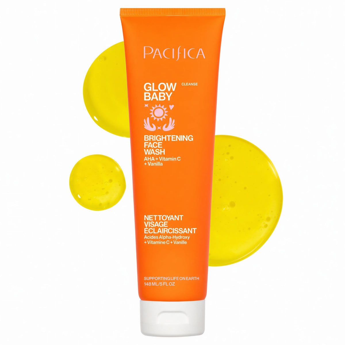 A squeeze tube of Pacifica Glow Baby Brightening Face Wash in Orange, shown against a white background with three yellow gel droplets behind it.