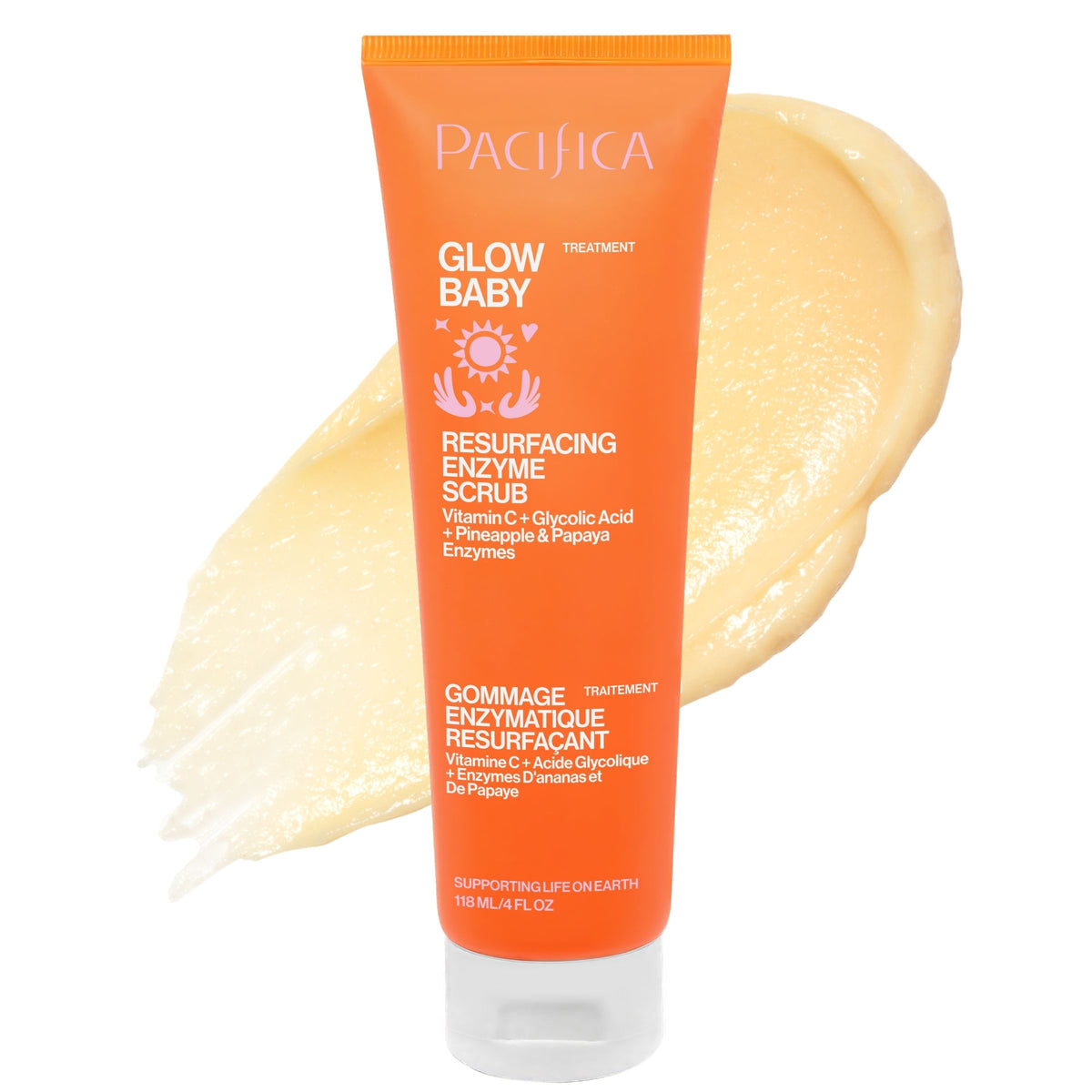 A tube of Pacifica Glow Baby Resurfacing Enzyme Scrub in bright orange, shown with a smear of the pale yellow scrub behind it on a white background.