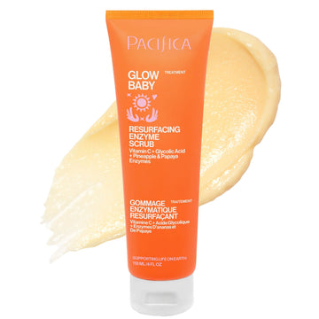 A tube of Pacifica Glow Baby Resurfacing Enzyme Scrub in bright orange, shown with a smear of the pale yellow scrub behind it on a white background.